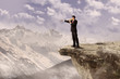 Businessman using speaker on cliff