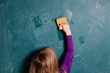 Young girl wiping chalkboard with wet sponge