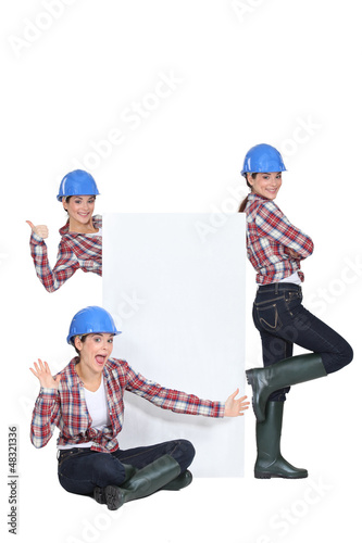 Photo: young craftswoman presenting a blank poster young craftswoman presenting a blank poster