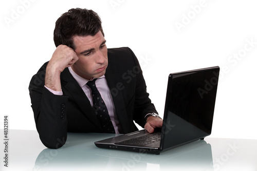 Photo: Annoyed businessman working on his laptop Annoyed businessman working on his laptop