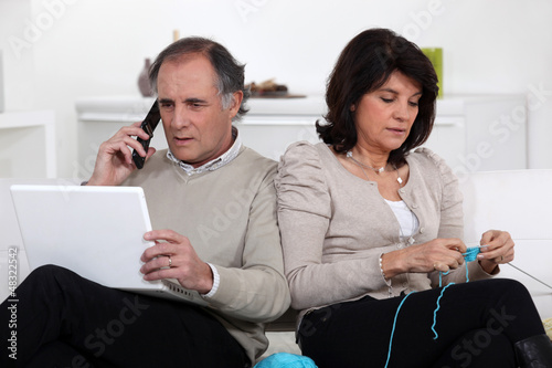 Photo: Man on phone and woman knitting at home Man on phone and woman knitting at home