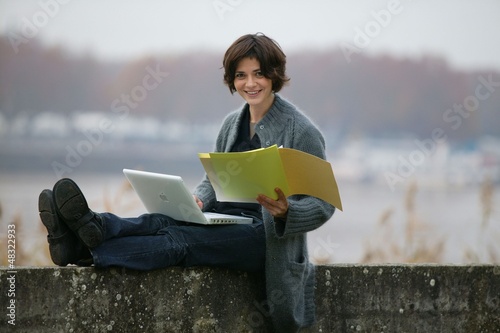 Photo: Woman studying whilst sat on a wall Woman studying whilst sat on a wall