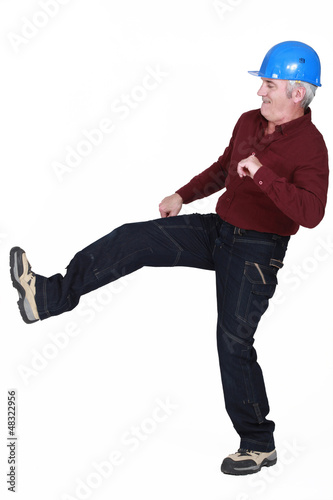 Photo: Construction worker kicking something Construction worker kicking something