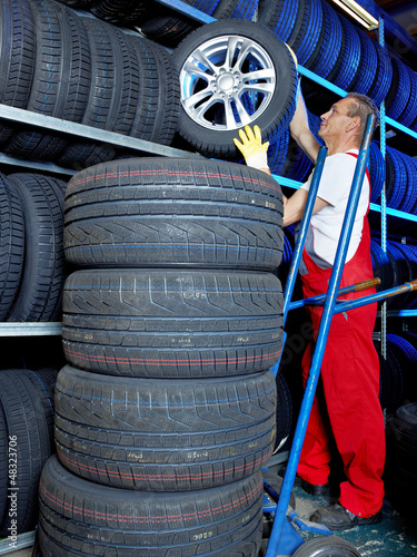 Photo: Car mechanics looking for a tire in a tire warehouse Car mechanics looking for a tire in a tire warehouse
