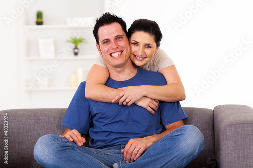 Photo: young loving couple hugging on sofa at home young loving couple hugging on sofa at home