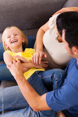 Photo: parents tickling little daughter on sofa parents tickling little daughter on sofa