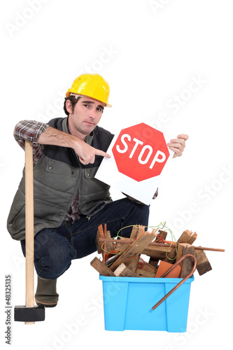 Photo: Labourer holding a stop sign while squatting Labourer holding a stop sign while squatting