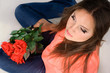 sad pretty girl holding red roses sitting on the floor