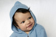 Newborn baby wearing blue cardigan smiles