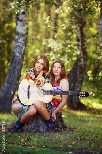 Photo: Hippie girls with guitar sitting on the stump Hippie girls with guitar sitting on the stump