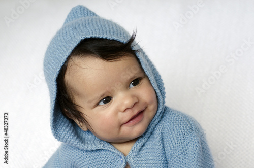 Photo: Newborn baby wearing blue cardigan smiles Newborn baby wearing blue cardigan smiles