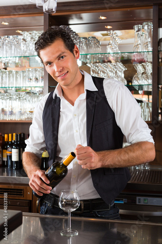 Photo: Barman standing behind bar with wine Barman standing behind bar with wine