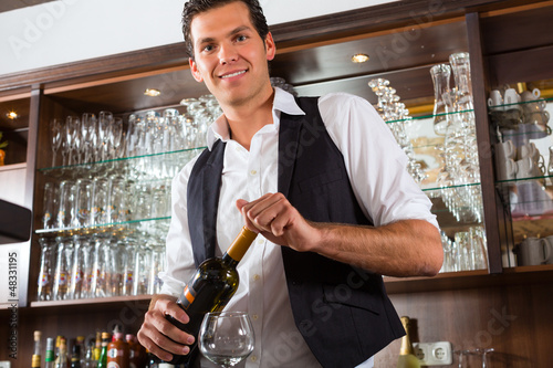 Photo: Barman standing behind bar with wine Barman standing behind bar with wine