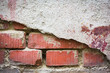 Red bricks showing through white broken plaster