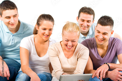 Photo: Young people sitting on a sofa, looking at a tablet Young people sitting on a sofa, looking at a tablet
