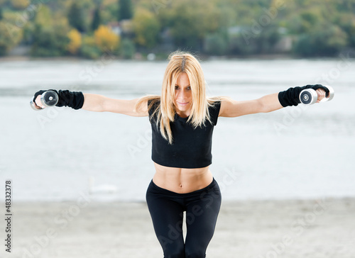 Photo: Beautiful fit woman exercising on the beach Beautiful fit woman exercising on the beach