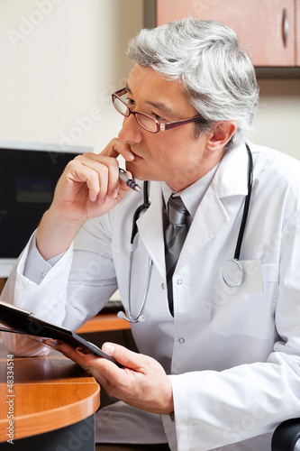 Photo: Thoughtful Doctor At Desk Thoughtful Doctor At Desk