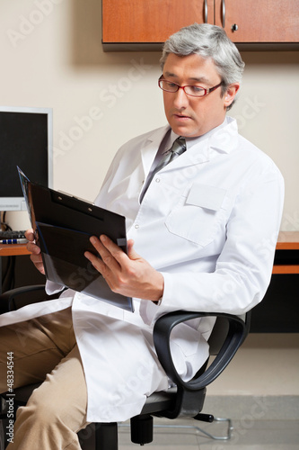 Photo: Mature Male Doctor Reading Mature Male Doctor Reading