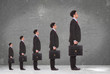5 business men holding briefcases standing in a row