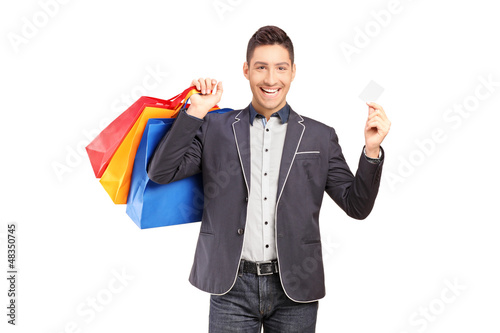 Photo: A smiling guy holding shopping bags and credit card A smiling guy holding shopping bags and credit card
