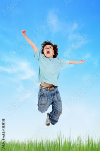 Photo: Adorable child jumping on the meadow Adorable child jumping on the meadow