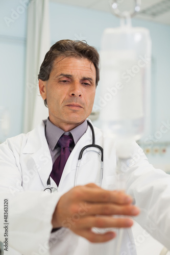 Photo: Thoughtful doctor in a hospital adjusting IV Thoughtful doctor in a hospital adjusting IV