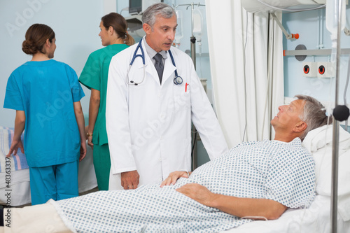 Photo: Patient lying in bed talking to doctor Patient lying in bed talking to doctor