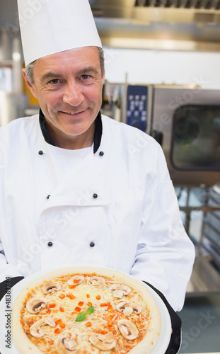 Photo: Smiling chef showing pizza Smiling chef showing pizza
