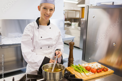 Photo: Smiling chef stirring soup Smiling chef stirring soup