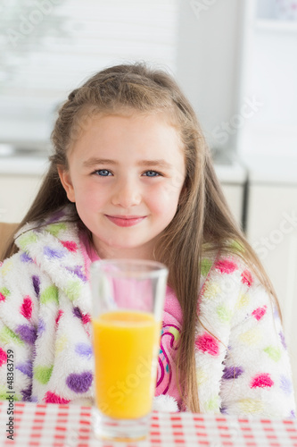 Photo: Little girl sitting while smiling with glass of orange juice Little girl sitting while smiling with glass of orange juice