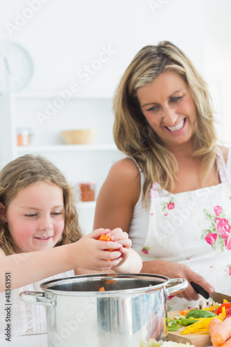 Photo: Laughing mother and daughter preparing vegetables Laughing mother and daughter preparing vegetables