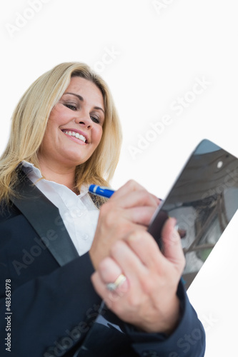 Photo: Happy business woman writing in the clipboard Happy business woman writing in the clipboard
