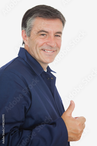 Photo: Happy mature mechanic showing thumbs up sign Happy mature mechanic showing thumbs up sign