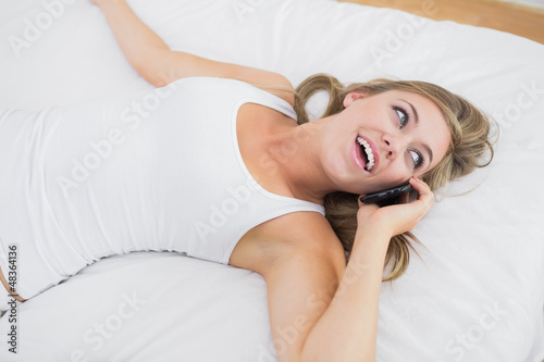 Photo: Calm woman phoning lying on the bed Calm woman phoning lying on the bed