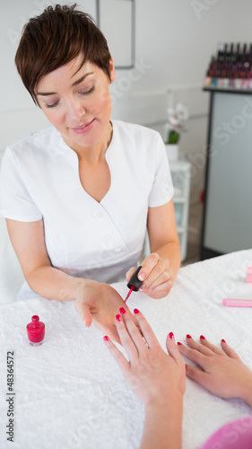 Photo: Woman applying nail varnish to finger nails Woman applying nail varnish to finger nails