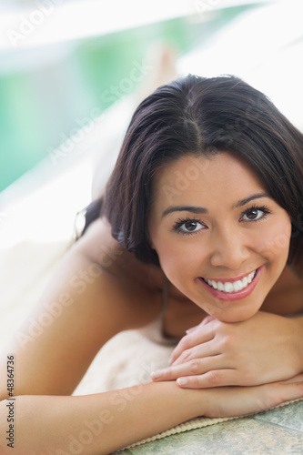 Photo: Woman lying on towel by pool Woman lying on towel by pool