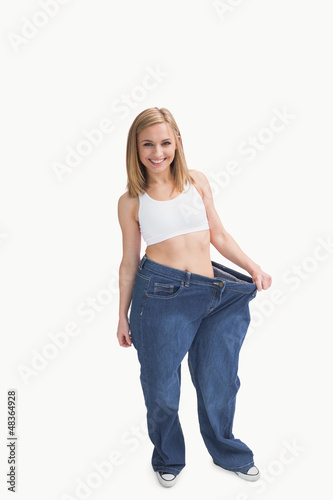Photo: Portrait of woman wearing old pants after losing weight Portrait of woman wearing old pants after losing weight