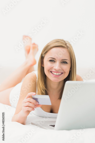 Photo: Portrait of woman doing online shopping in bed Portrait of woman doing online shopping in bed