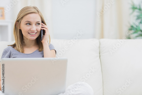 Photo: Casual woman using laptop and cellphone at home Casual woman using laptop and cellphone at home