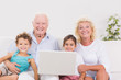 Photo: Smiling grandparents with children using a pc Smiling grandparents with children using a pc