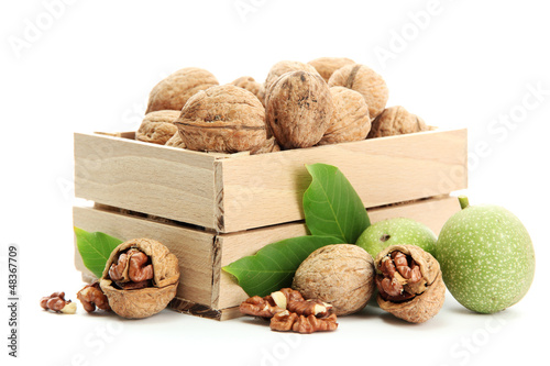 Photo: walnuts with green leaves in woooden crate, isolated on white walnuts with green leaves in woooden crate, isolated on white
