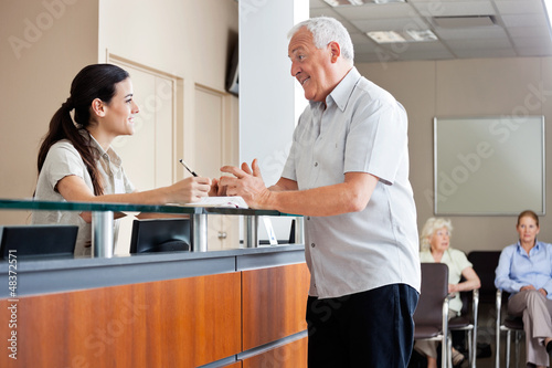 Photo: Man Communicating With Female Receptionist Man Communicating With Female Receptionist