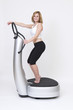 Sportliche schlanke Frau trainiert stehend auf Powerplate
