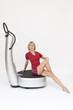 Junge sportliche Frau trainiert sitzend auf einer Powerplate