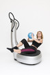 Junge sportliche Frau sitzend mit Ball auf Powerplate