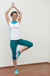 Eine junge Sport Trainerin zeigt die Yoga Figur der Baum