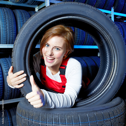 Photo: Female apprentice for mechanic shows thumb up for tire changing Female apprentice for mechanic shows thumb up for tire changing