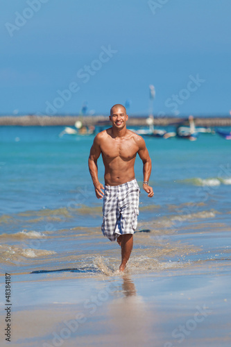 Photo: young man running on beach young man running on beach