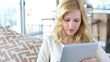 Blond girl sitting in sofa with digital tablet