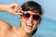 Playful happy woman with red glasses on the beach